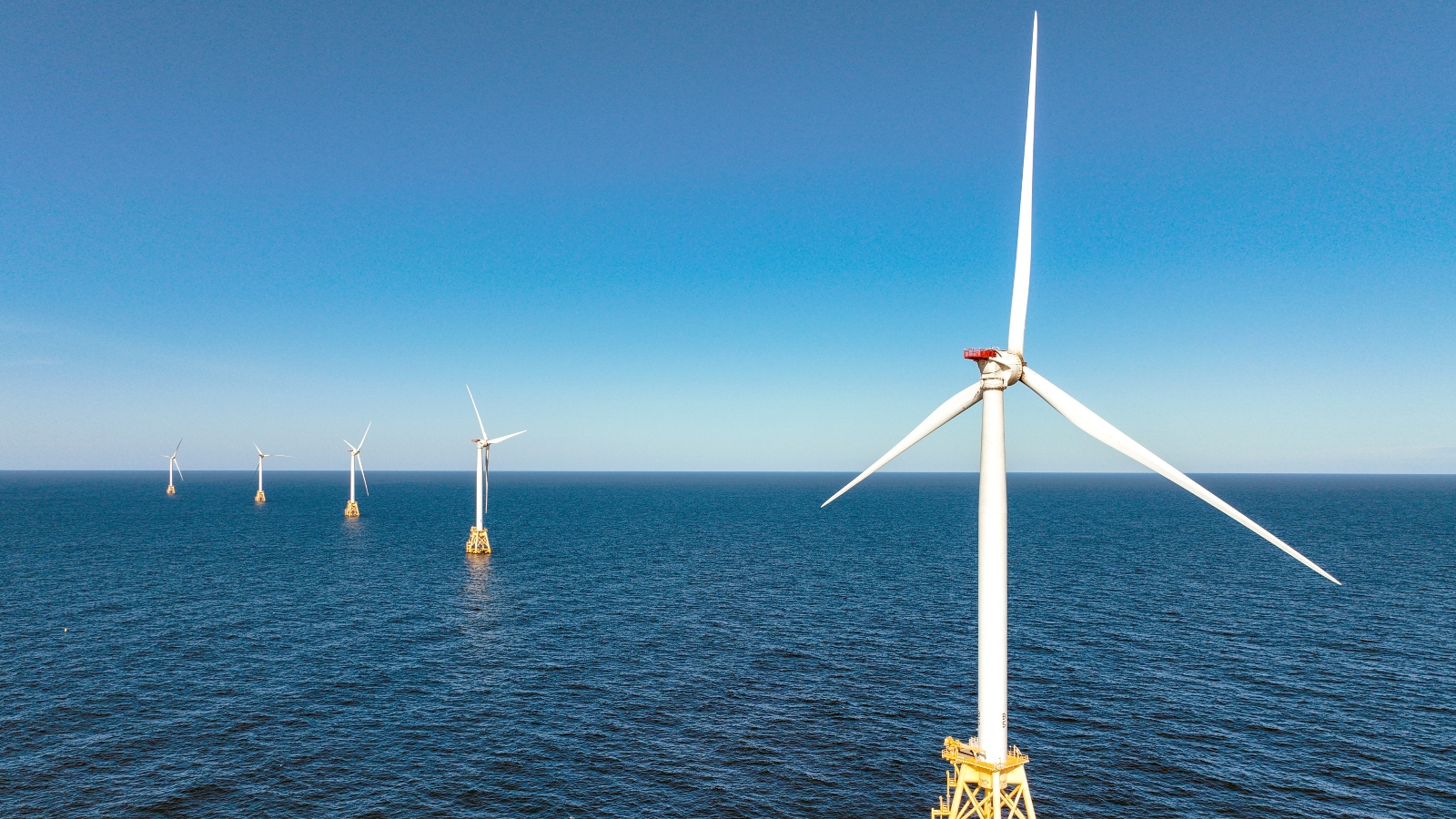 Several wind turbines stand in the middle of the ocean