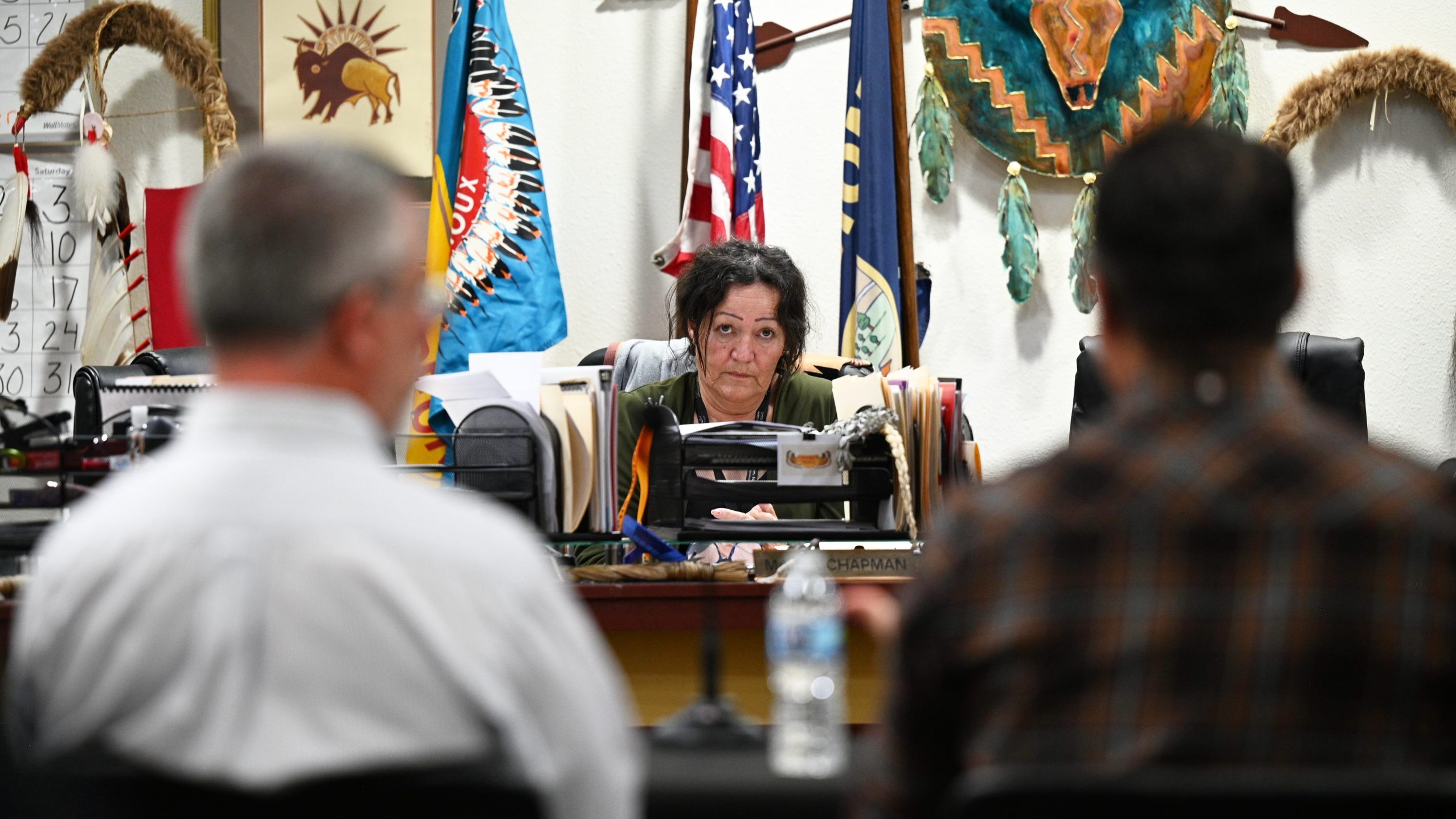 Marva Chapman sitting at a desk, looking at two Bureau of Land Management officials sitting across from her