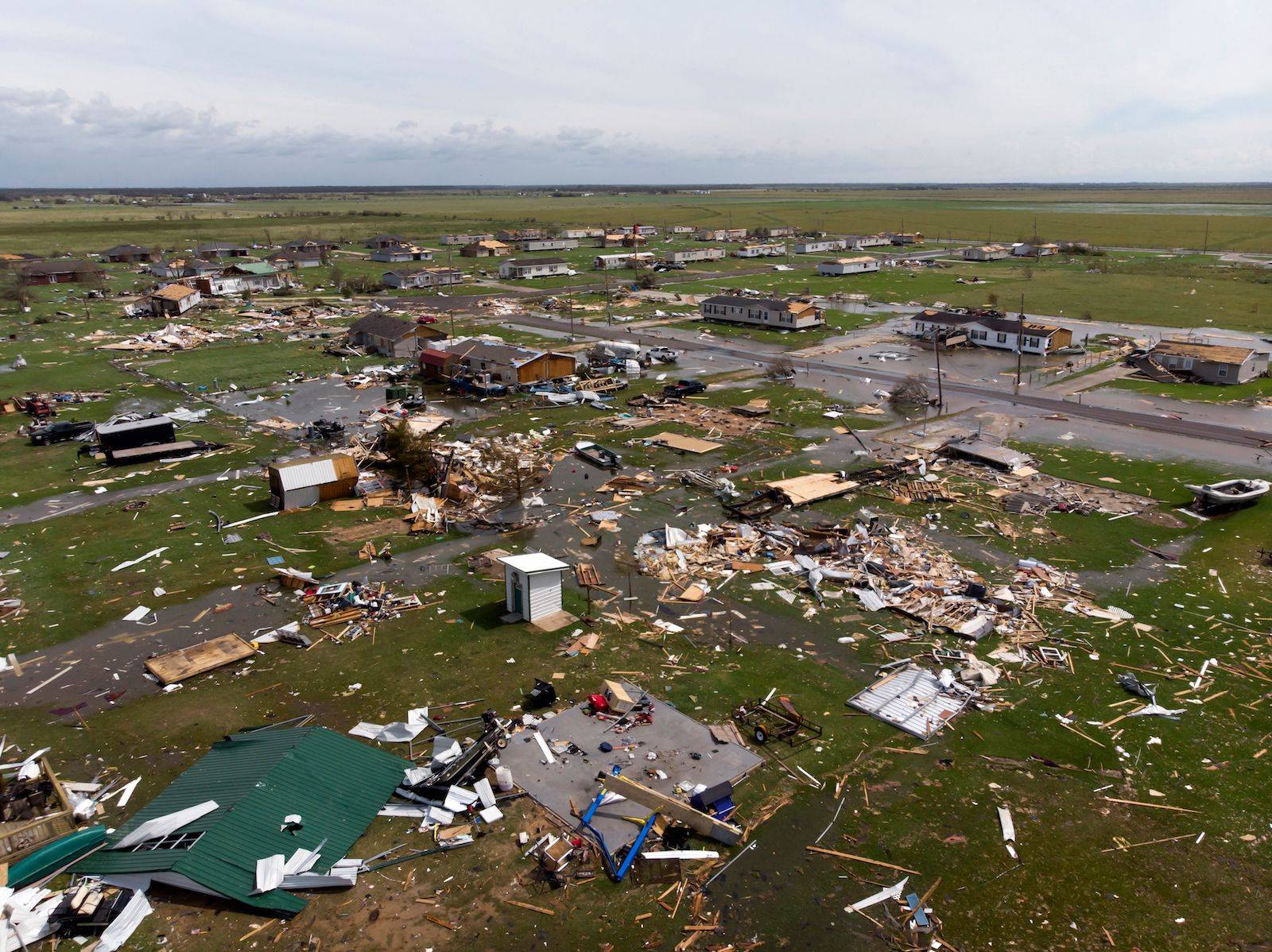 An aerial image of debris and wreckage lying on the green earth, extending far back to the horizon