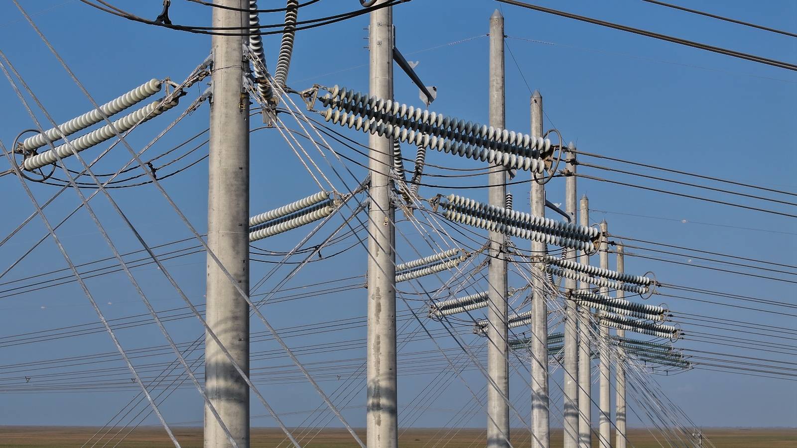 A series of power lines stand against a blue sky.