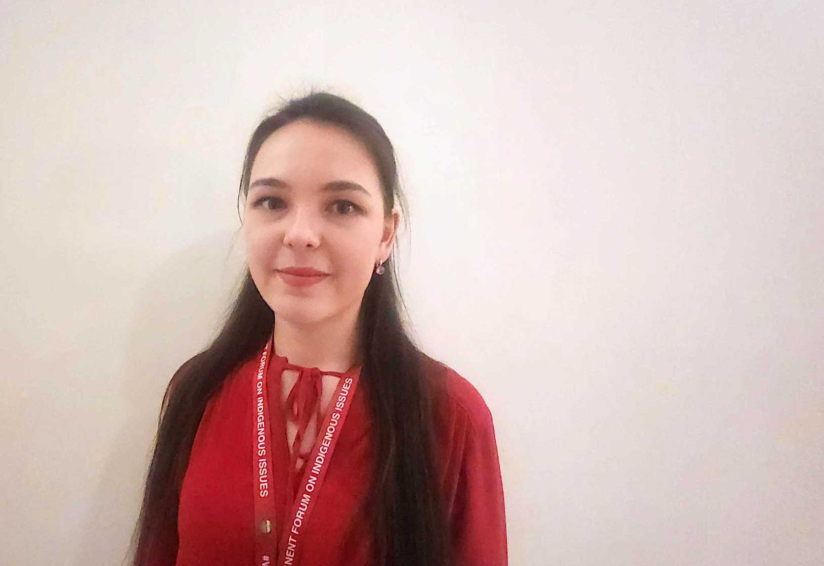 A young woman in a red shirt poses for a photo
