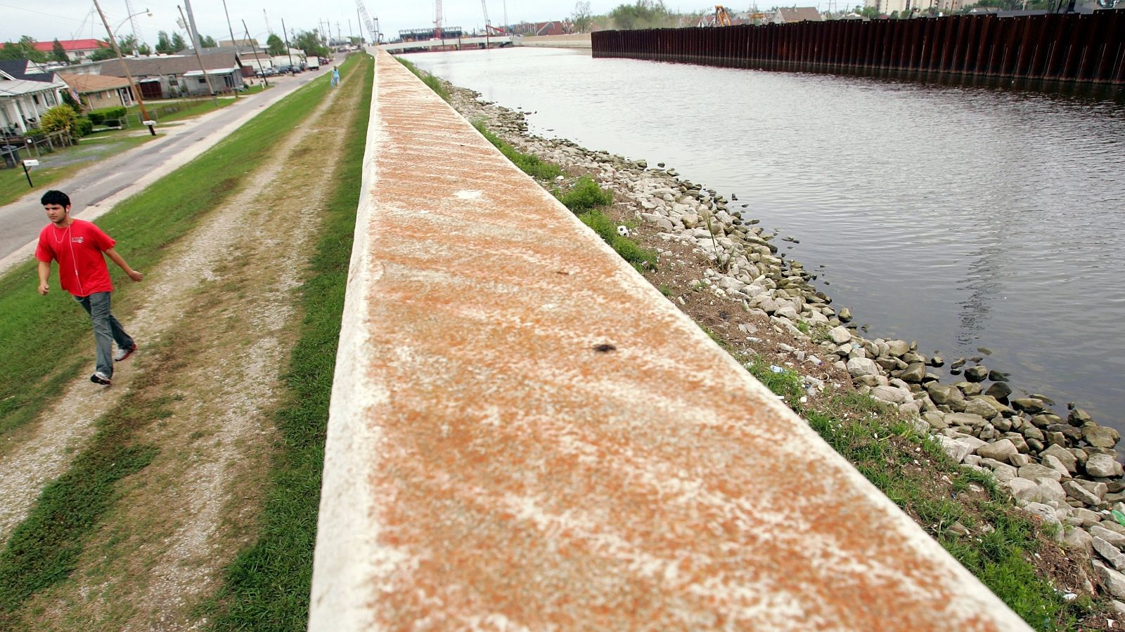 A pedestrian walks along the 17th Street Canal in 2007, near the levee wall that failed during Hurricane Katrina. The Corps of Engineers built a new levee system around New Orleans after the storm, but that system itself is sinking as land subsides.