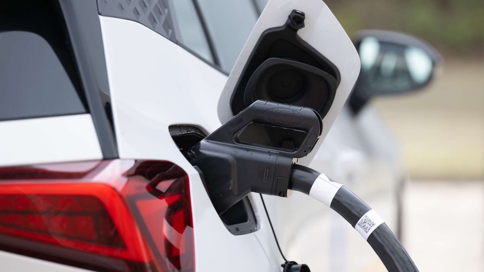 A white electric vehicle has a charger attached to it