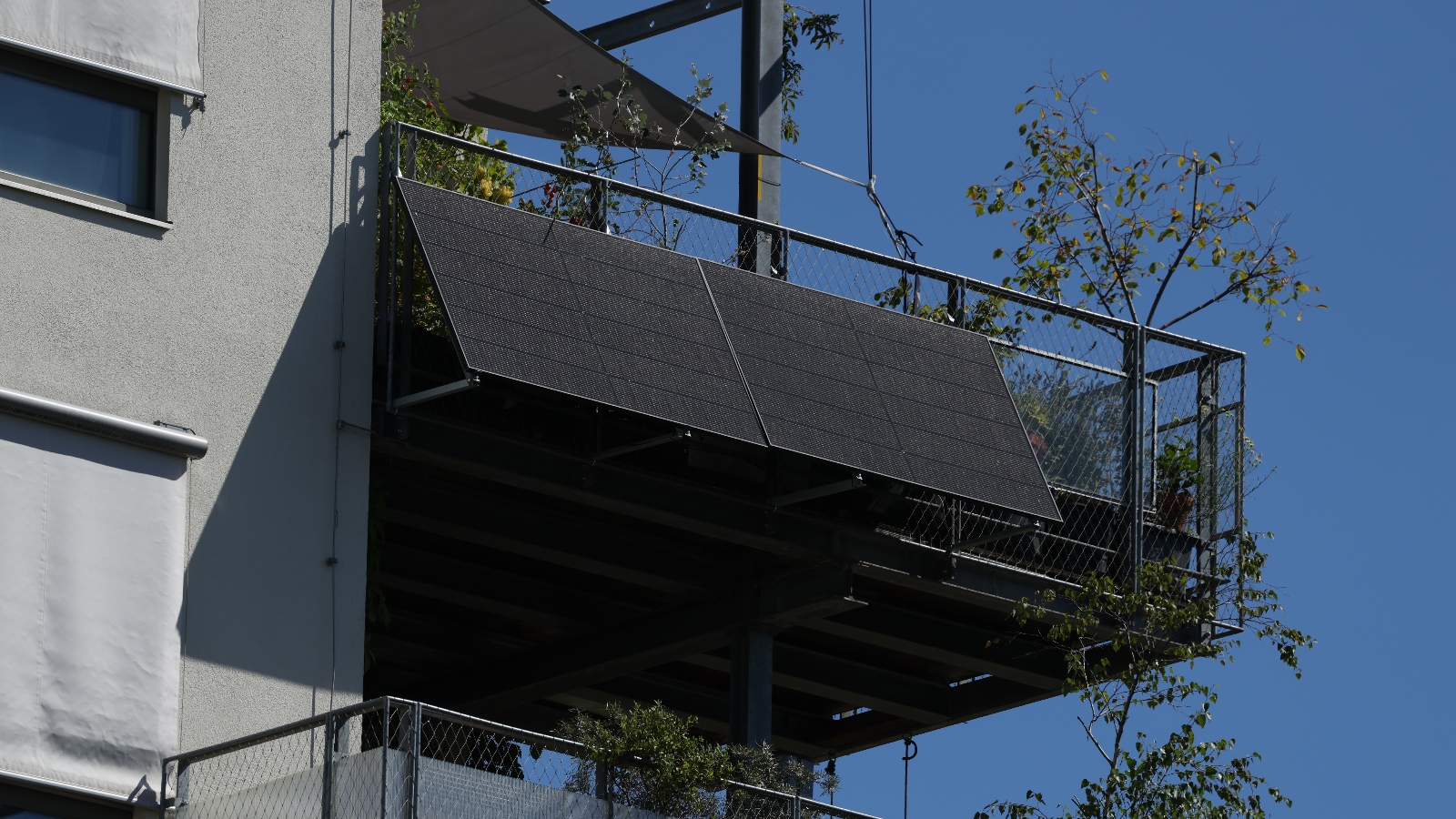A solar panel sits on the outside of an apartment balcony