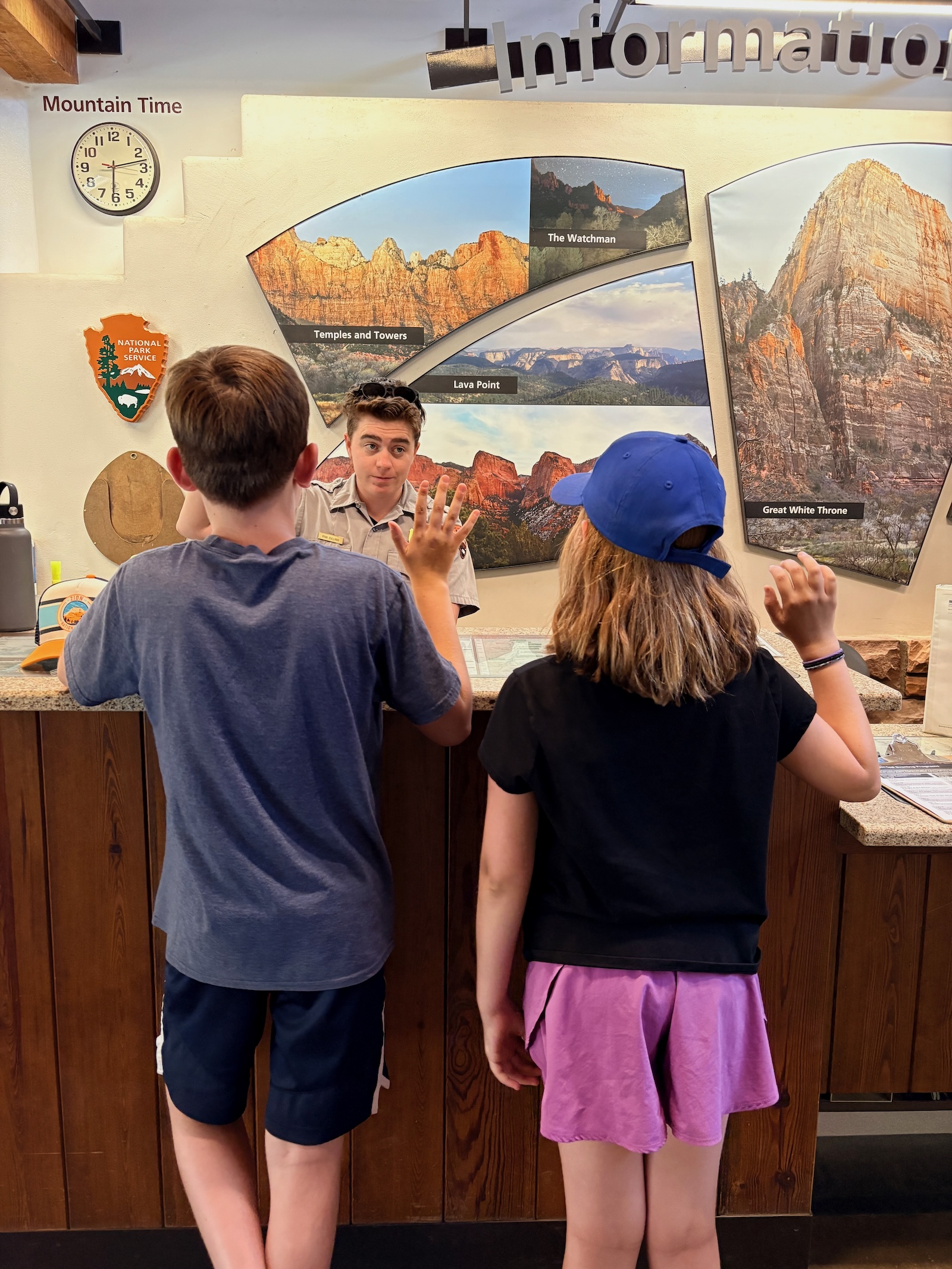 two children face a park ranger with their hands raised