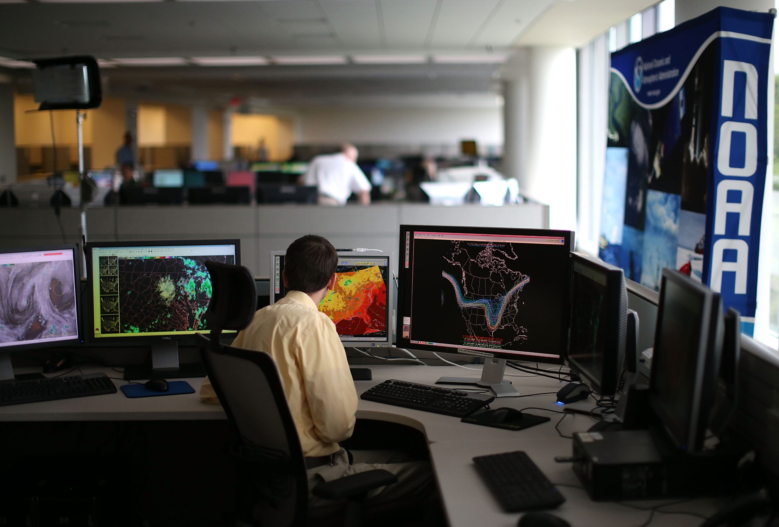 A man looks at multiple screens showing science readings at NOAA